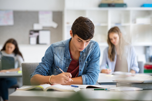 Imagem de um jovem estudante concentrado escrevendo sua redação nota mil no Enem