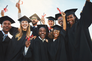 A imagem mostra um grupo diverso de estudantes comemorando a formatura, todos usando becas e segurando seus diplomas. A cena reflete a alegria e a diversidade no ensino superior.