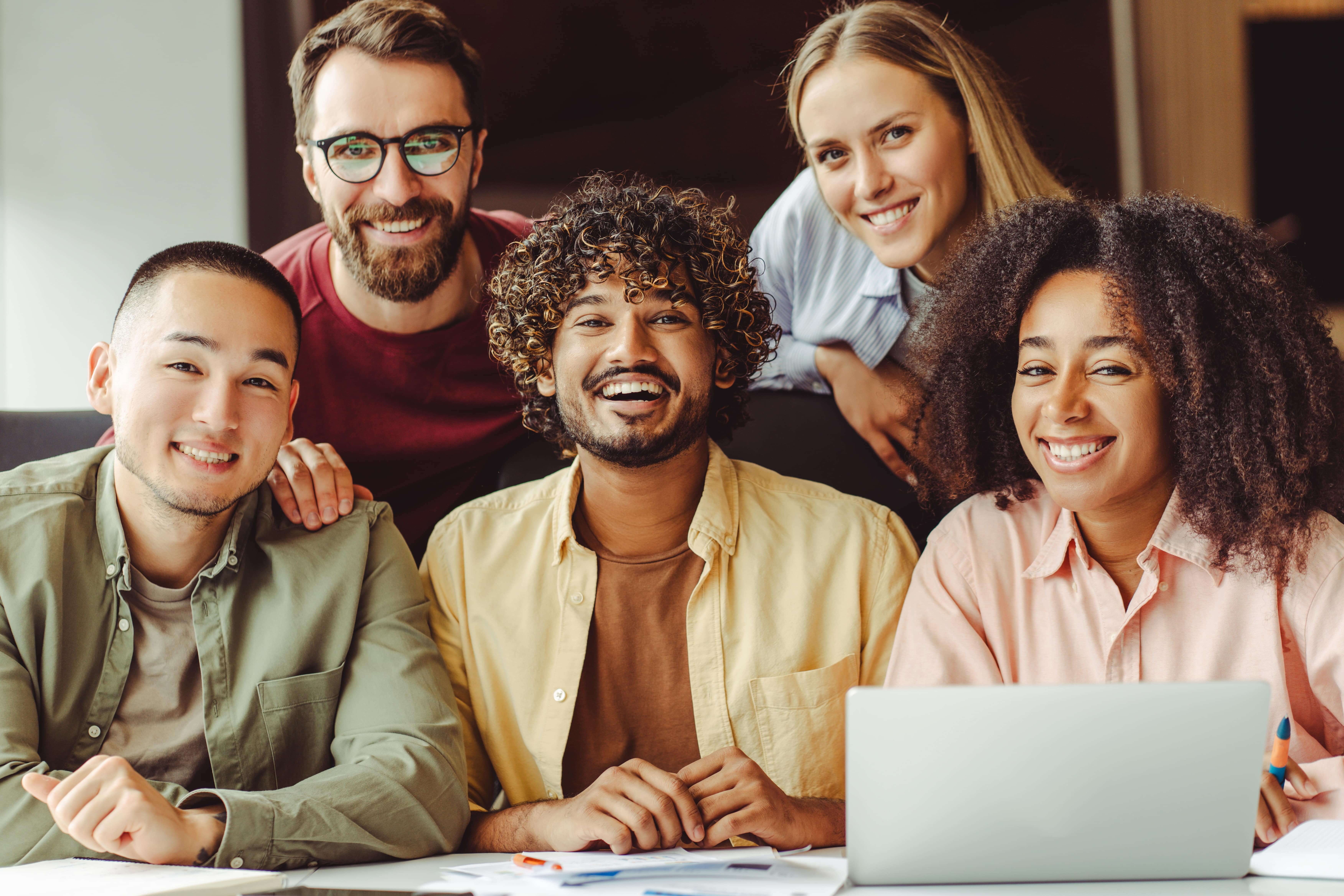 Imagem de um grupo de pessoas juntas em um escritório, olhando sorrindo para câmera.