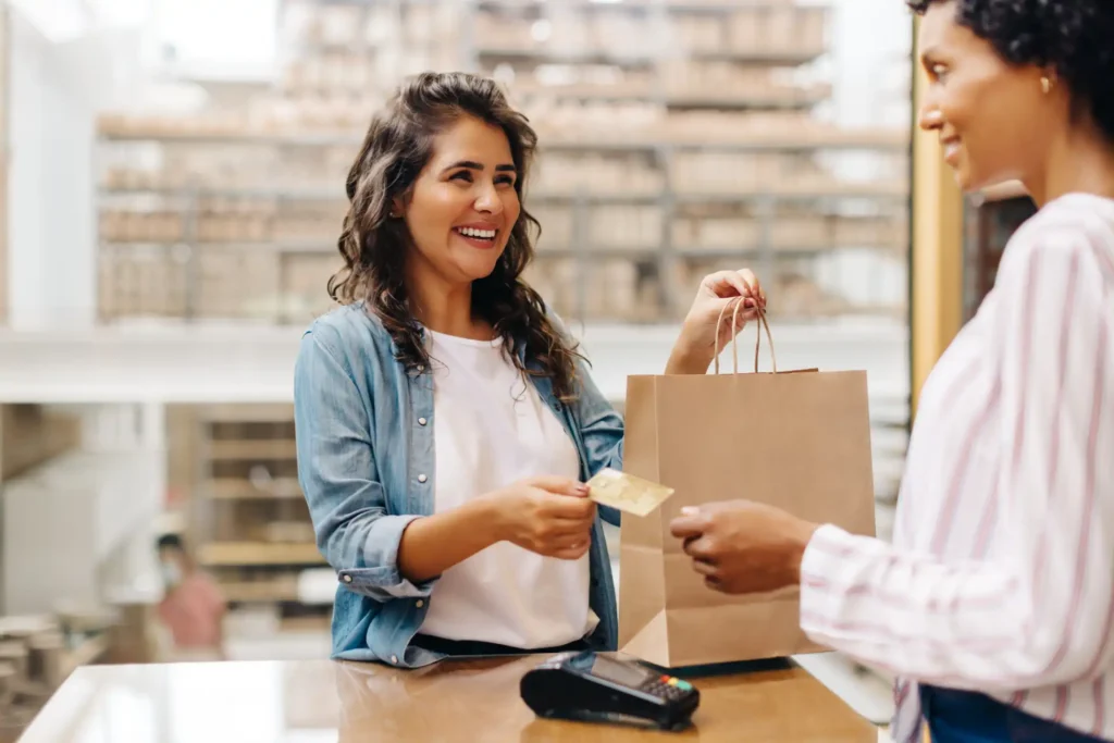 Mulher comprando em uma loja, sorrindo e recebendo um pagamento, conceito de se dar bem em vendas, atendimento ao cliente, sucesso nas vendas.