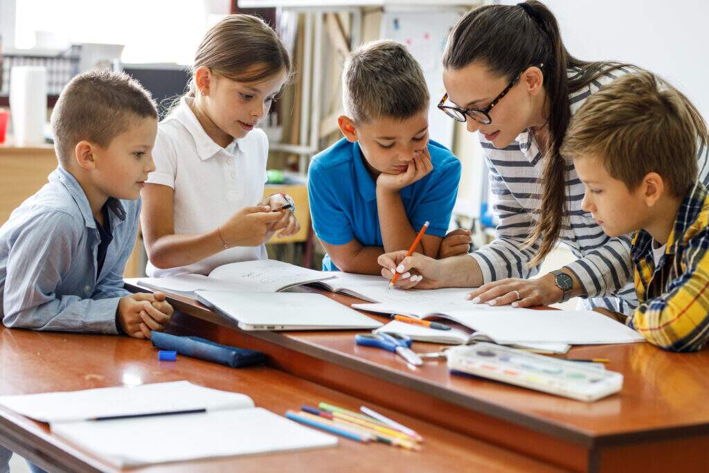 Professora orientando alunos em atividade educacional durante a formação em licenciatura em pedagogia, desenvolvendo práticas pedagógicas em sala de aula.