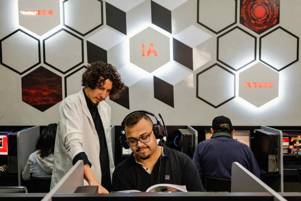 Professor orientando aluno com headphone em laboratório da Prepara IA 
— a interação humana é o diferencial que a inteligência artificial 
não consegue substituir
