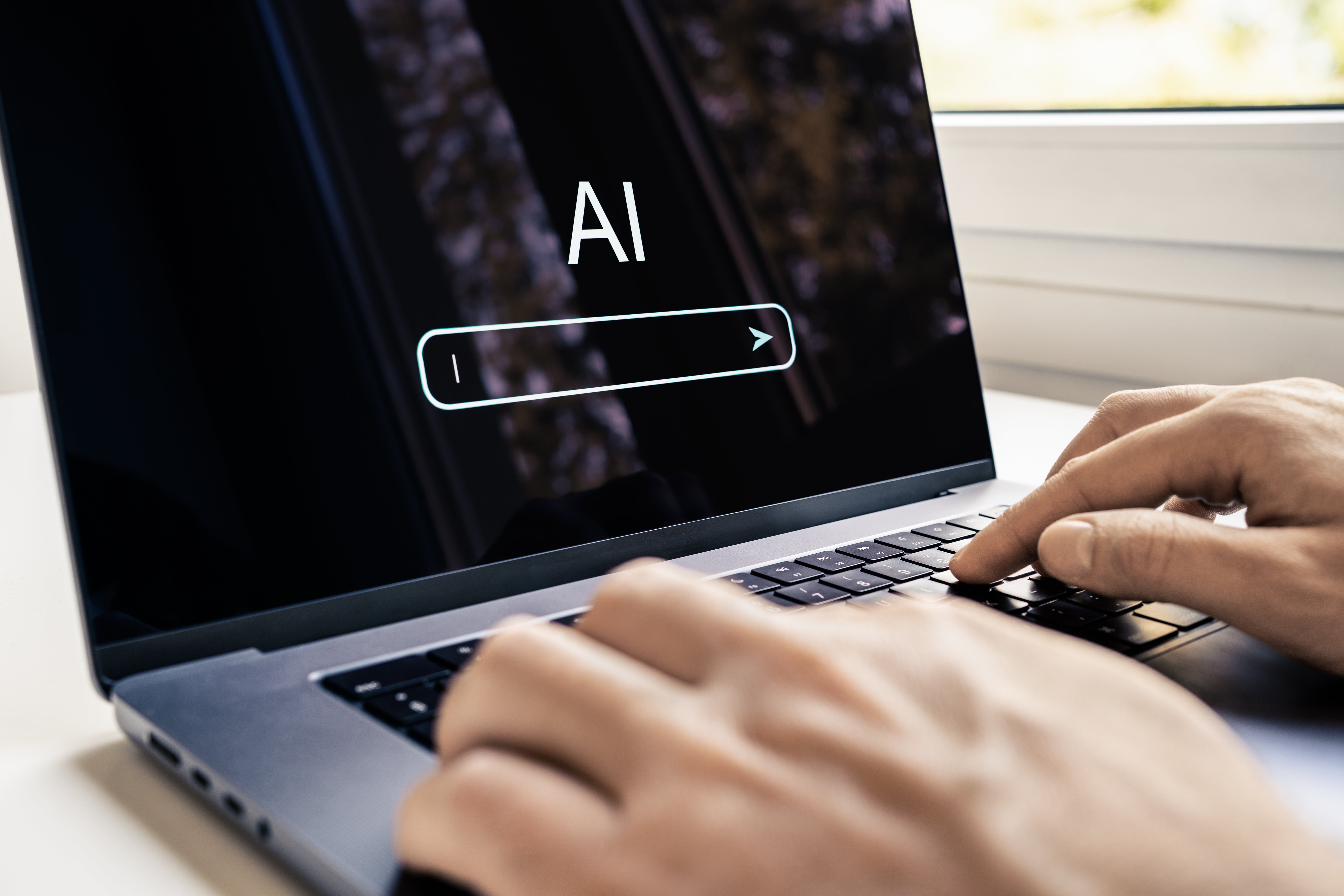 Pessoa digitando em notebook com a palavra AI na tela, representando o que é inteligência artificial e seu impacto no futuro profissional.